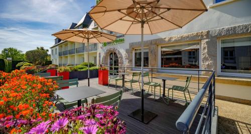 a patio with tables and umbrellas in front of a building at Hôtel La Résidence des Artistes in Roscoff