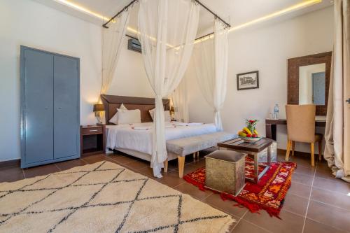 a bedroom with a canopy bed and a desk at Taj Atlas Wellness Boutique Hôtel & Spa in Amizmiz