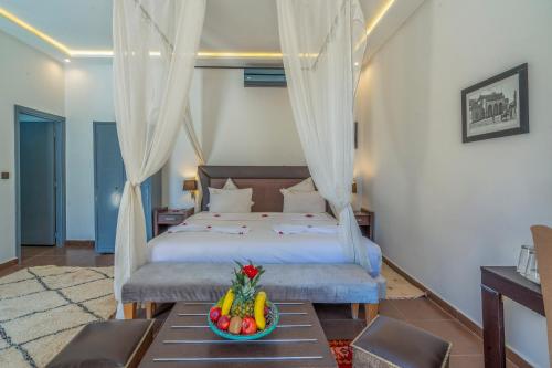 a bedroom with a bed with a bowl of fruit on a table at Taj Atlas Wellness Boutique Hôtel & Spa in Amizmiz