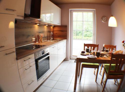 cocina con mesa y fogones horno superior en Ferienwohnung Lüneburger Heide en Schneverdingen