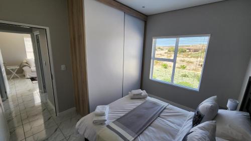 One Bedroom Unit with Kitchenette in Langebaan Country Estate - Solar Power في لانجيبان: غرفة نوم بسرير ونافذة بها مناشف