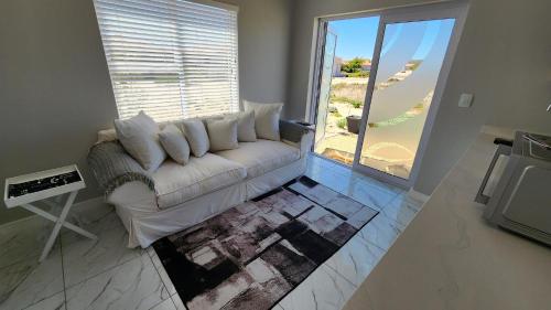 a white couch in a living room with a large window at One Bedroom Unit with Kitchenette in Langebaan Country Estate - Solar Power in Langebaan