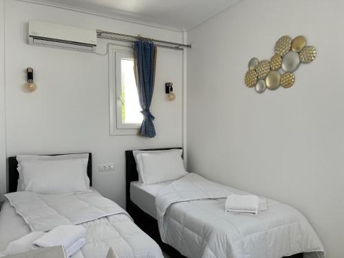 two beds in a room with white walls and a window at 3 Bedroom House included free car rental in Perissa