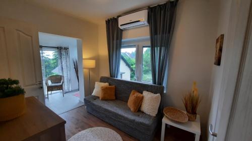 a living room with a gray couch and a window at Borostyán nyaralóház in Fonyód