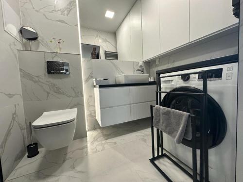uma casa de banho com um WC e uma máquina de lavar e secar roupa em Apartament Centrum II em Bydgoszcz