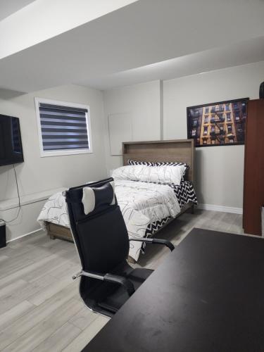 ein Schlafzimmer mit einem schwarzen Stuhl und einem Bett in der Unterkunft Modern Apartment London Ontario in London