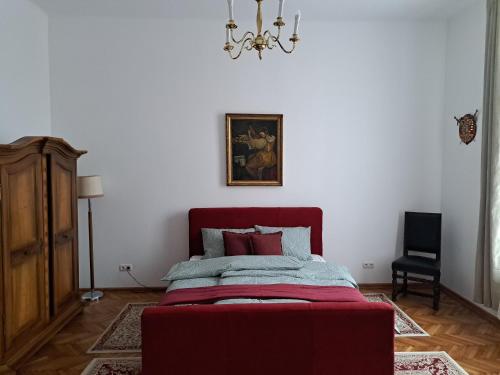 a bedroom with a red bed and a chandelier at Weisz Castle style Apartment - With Free Private Parking,Wifi in Carei