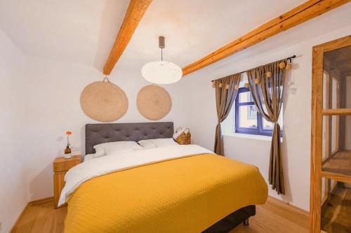 1 dormitorio con 1 cama amarilla y 2 luces colgantes en Transylvania Village House 