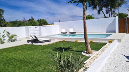 un patio trasero con una piscina con 2 sillas y una palmera en Villa Turquesa, en Zahora