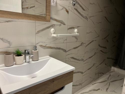 baño con lavabo blanco y pared de mármol en Apartman Time out 1, en Sombor