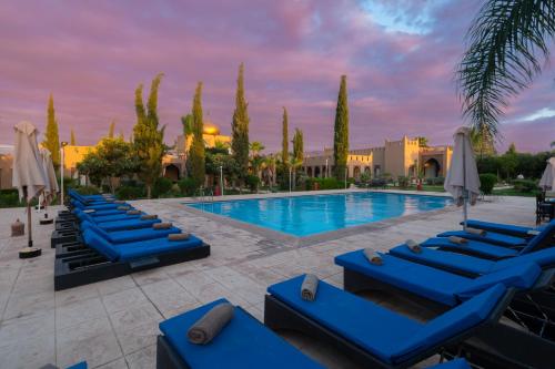 a pool with blue lounge chairs and umbrellas at Taj Atlas Wellness Boutique Hôtel & Spa in Amizmiz