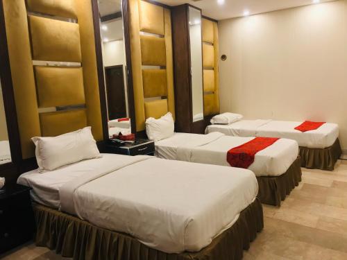 Habitación de hotel con 2 camas y espejo en Pool & Park Hotel, en Lahore