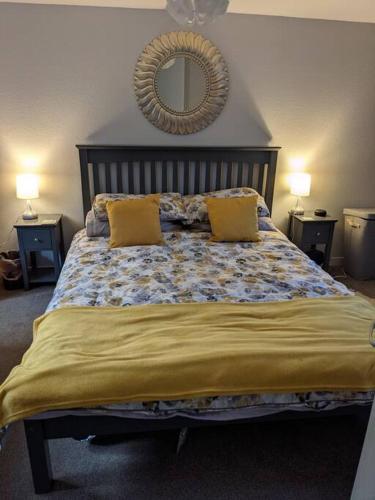 a bedroom with a bed with two yellow pillows and a mirror at Applegrove, perfect 2 bed bungalow, Fortrose in Fortrose