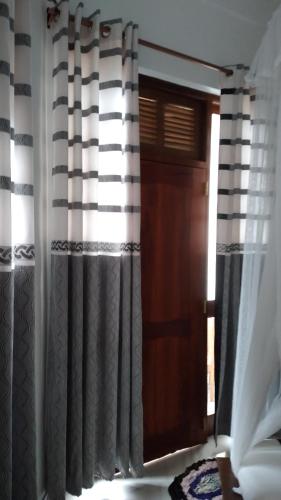 a room with a window with curtains and a door at Holly House Homestay in Ella