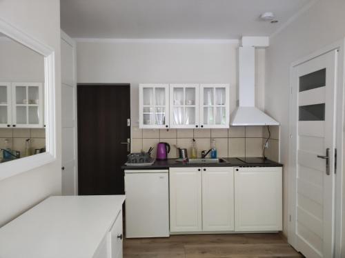 a white kitchen with white cabinets and a sink at Kamionka in Sopot