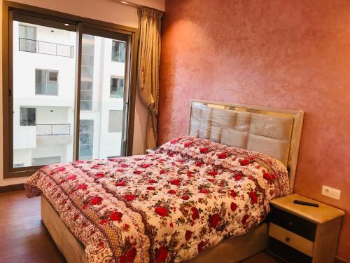 Un dormitorio con una cama con colcha floral y una ventana. en THE luxurious and romantic pearl apartment, en Mohammedia