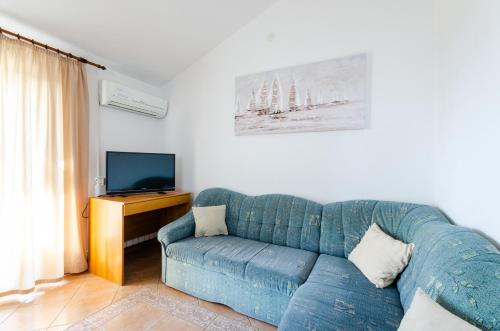 a living room with a blue couch and a tv at Apartmani Sunčica Selce in Selce
