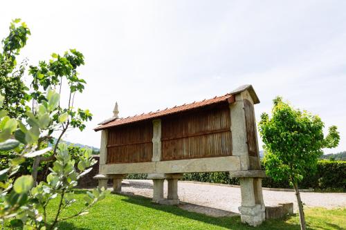 mały budynek siedzący w trawie na dziedzińcu w obiekcie Quinta da Carvalhosa w mieście Cabeceiras de Basto