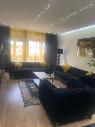 a living room with black couches and a table at Charme et confort in Mulhouse