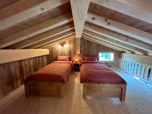 2 camas en una habitación con paredes de madera en chalet du Champel jacuzzi, en Saint-Gervais-les-Bains