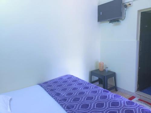 1 dormitorio con 1 cama de color púrpura y TV en Colva Beach Samaira GuestHouse & Apartments, en Colva