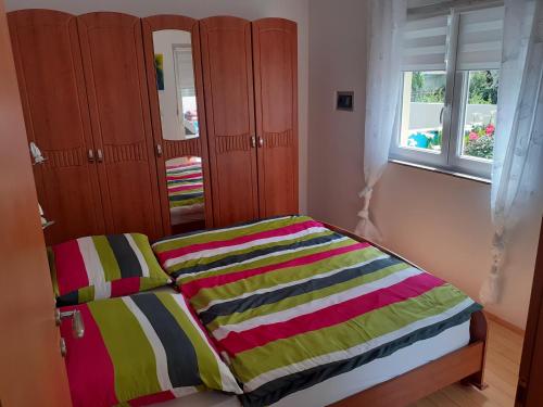 a bedroom with a bed with a colorful striped blanket at Apartman Nada in Ližnjan