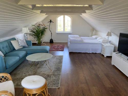 a living room with a blue couch and a bed at Modern house, views over the fields 5 min to beach in Halmstad