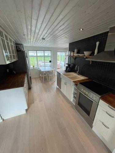 uma grande cozinha com electrodomésticos brancos e piso em madeira em Modern house, views over the fields 5 min to beach em Halmstad