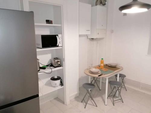 une petite cuisine blanche avec une table et des chaises dans l'établissement Appartement meublé proche du centre - Wifi/Parking, à Clermont-Ferrand