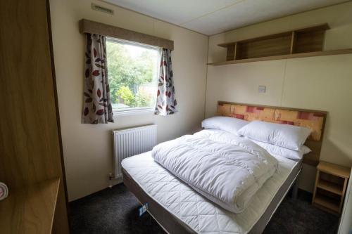 a bed in a small room with a window at Great 8 Berth Caravan For A Staycation In Clacton-on-sea Ref 26436e in Clacton-on-Sea