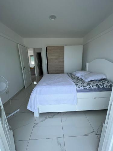 een witte slaapkamer met een bed en een tegelvloer bij Villa C in Vieux-Habitants
