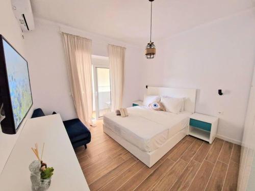 a bedroom with a white bed with a blue face on it at Rafaela Sea Apartment in Sarandë