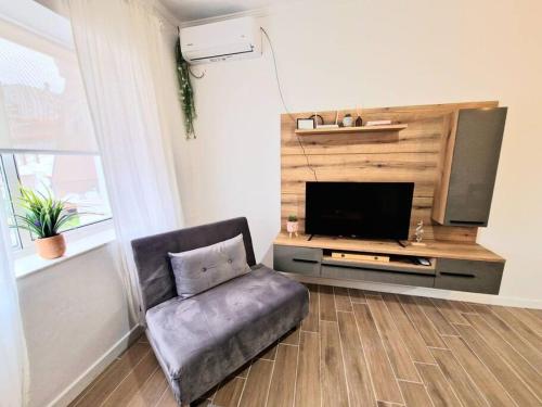 a living room with a chair and a flat screen tv at Rafaela Sea Apartment in Sarandë