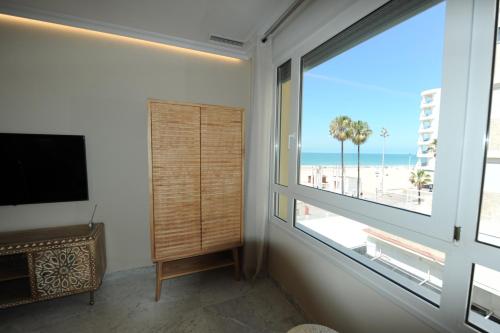 a living room with a large window with a view of the beach at Apartamento reformado con vistas al mar in Cádiz