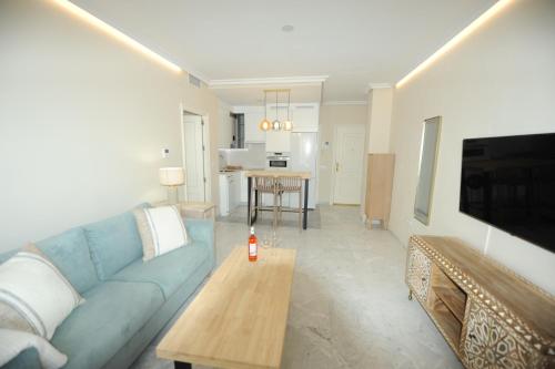 a living room with a blue couch and a table at Apartamento reformado con vistas al mar in Cádiz
