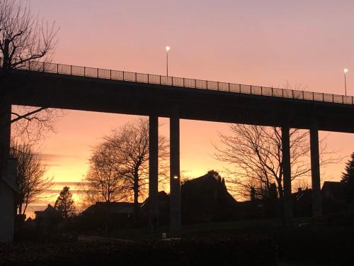 a bridge in front of a sunset with trees at Sundkig fra 1. Sal in Svendborg
