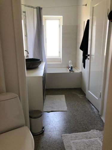 uma casa de banho com um lavatório, um WC e uma janela. em Sundkig fra 1. Sal em Svendborg