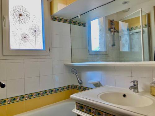 een badkamer met een wastafel, een bad en een spiegel bij Les Restanques glycines 2066 in Grimaud