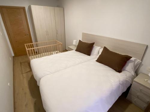 1 dormitorio con 2 camas con sábanas blancas y almohadas marrones en SOPHIE APARTAMENTOS en Burela de Cabo
