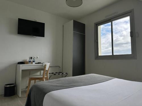 a bedroom with a bed and a desk and a window at Hôtel Restaurant Le Mur du Roy in Sarzeau