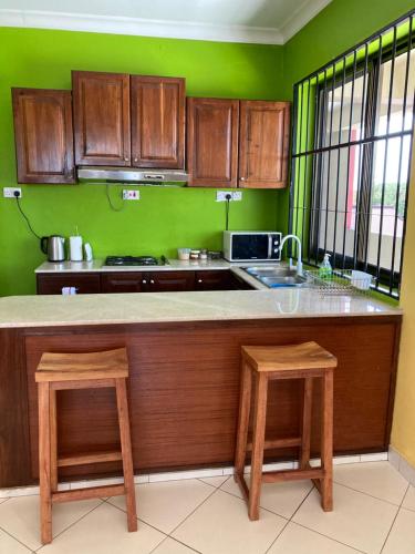 a kitchen with wooden cabinets and a counter with two stools at the bib By Jevas in Dar es Salaam