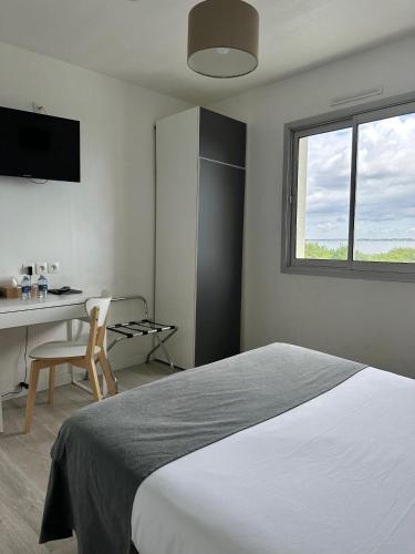 a bedroom with a bed and a desk and a window at Hôtel Restaurant Le Mur du Roy in Sarzeau