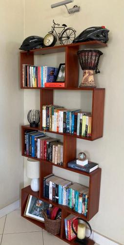 a book shelf with books and a clock on a wall at TheGatsbyStyle By Jevas in Dar es Salaam