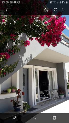 eine Terrasse mit rosa Blumen, einem Tisch und Stühlen in der Unterkunft Kostas apartament in Kontokali