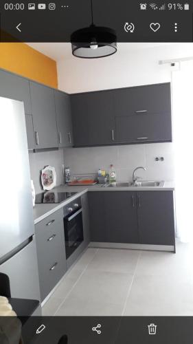 eine Küche mit schwarzen und weißen Schränken und einem Waschbecken in der Unterkunft Kostas apartament in Kontokali