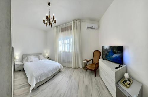 a white bedroom with a bed and a television at La Villetta nel Delta in Mesola