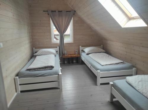 Cette chambre mansardée comprend 2 lits et une fenêtre. dans l'établissement Domki na Polnej, à Grzybowo