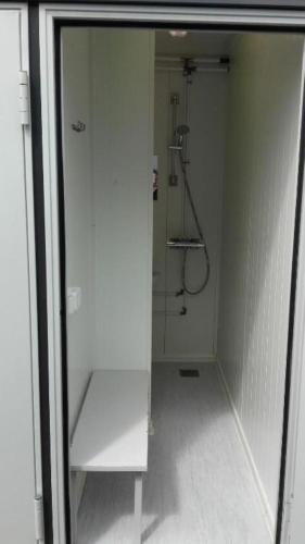 a white bathroom with a shower and a glass door at Varuna jachta in Nida
