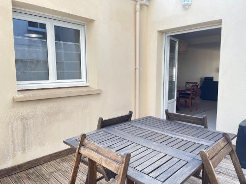 a wooden table and chairs on a porch with a window at Le Mulberry in Bayeux