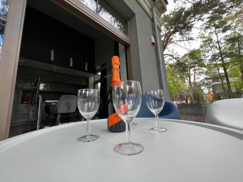 a table with three wine glasses and a bottle on it at Villa Comfort in Palanga